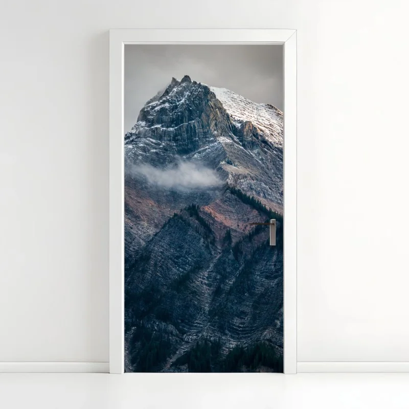 Adesivo per porta maestoso picco innevato tra rocce e nebbia